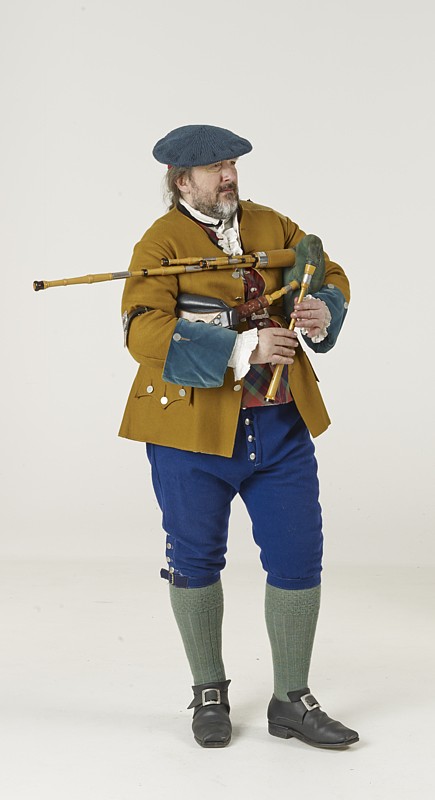 Quest in historischer schottischer Lowland-Tracht in Kniebundhose mit kurzer Jacke und flacher Schottenmütze, die Border-Pipes spielend